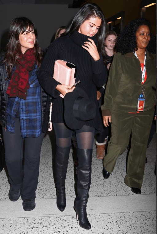 Selena gomez black sweater dress knee high boots pink bag black hat.png
