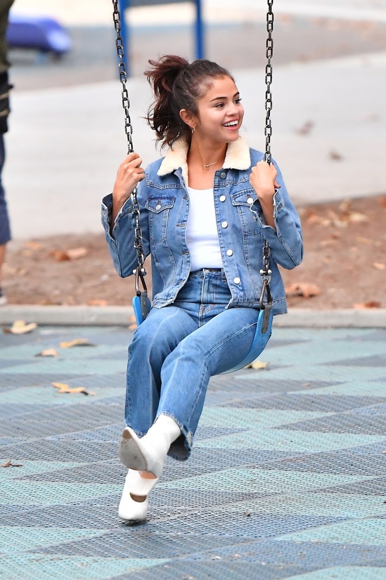 Selena gomez denin jacket borg collar white boots sitting on a swing in the park 2 November 2017