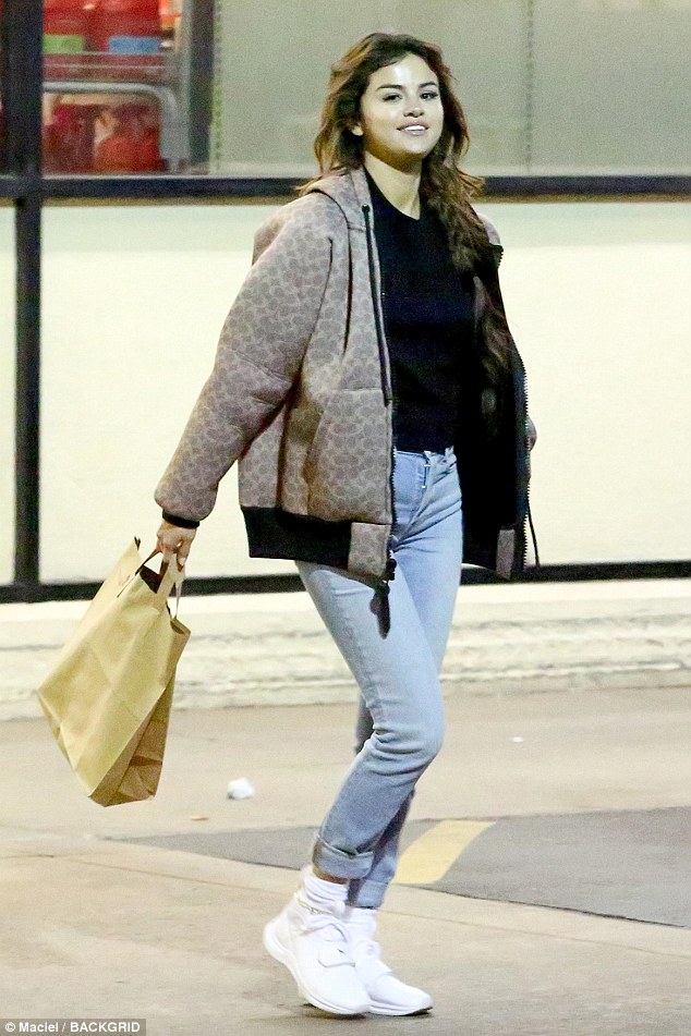 Selena Gomez style clothes fashion brown bomber jacket jeans black top white trainers February 21 2018