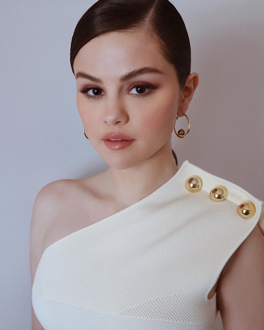 where to get Selena Gomez white asymmetric dress gold buttons gold hoop earrings 8 February 2021 Photo Kate Young